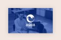 Two men in an office setting shake hands across a desk. A white wave logo and the text AQUA Your company logo design are overlaid at the center of the image. The image has a blue filter.