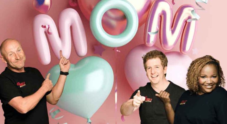 Three smiling people stand in front of pastel heart and letter balloons spelling MOM on a pink background with stars and ribbon decorations.