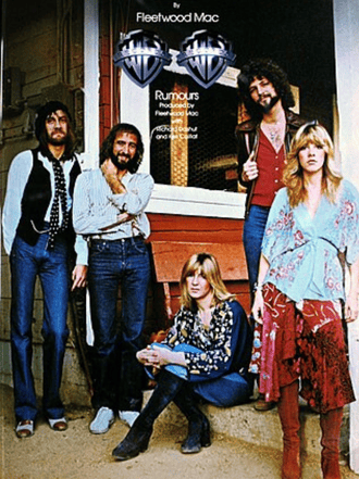 Five members of Fleetwood Mac pose outside a building; three stand and two sit on a step, all dressed in 1970s-style clothing. The iconic âFleetwood Mac Rumoursâ album cover title appears above them.