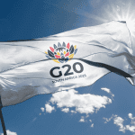 A white flag with a colorful flower emblem and the text G20 SOUTH AFRICA 2025 flutters against a sunny, blue sky, symbolizing new business opportunities on the global stage.