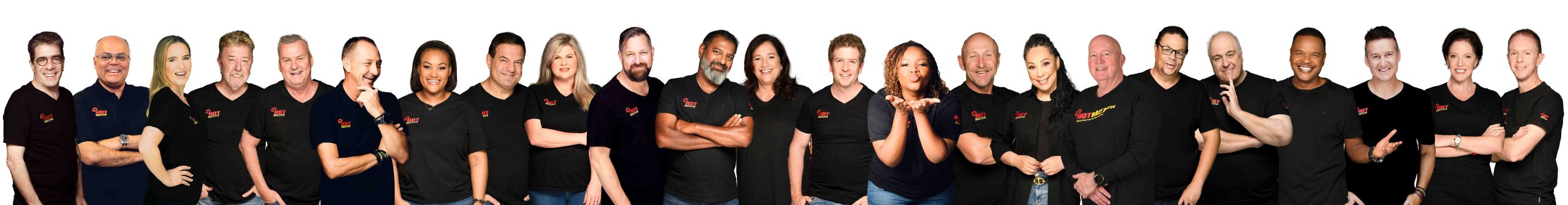 A group of 20 people, diverse in gender and appearance, stand together in a row against a white background, all wearing black shirts and smiling at the camera to advertise with HOT 1027.